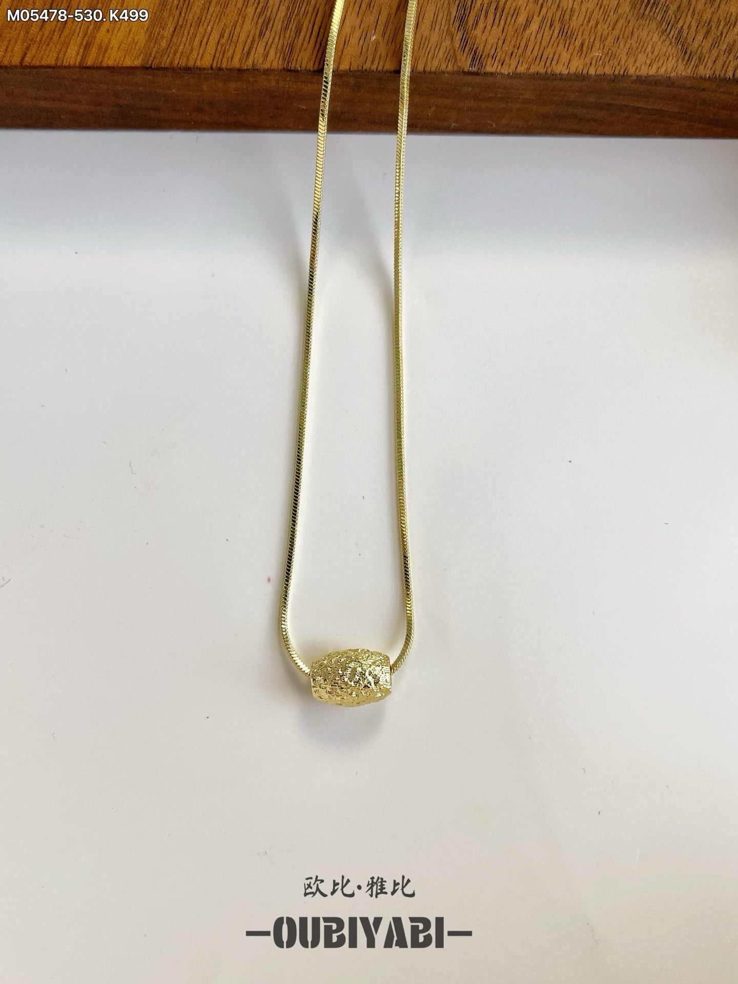 Two-tone metal necklace with silver and gold chains and a carved pendant.