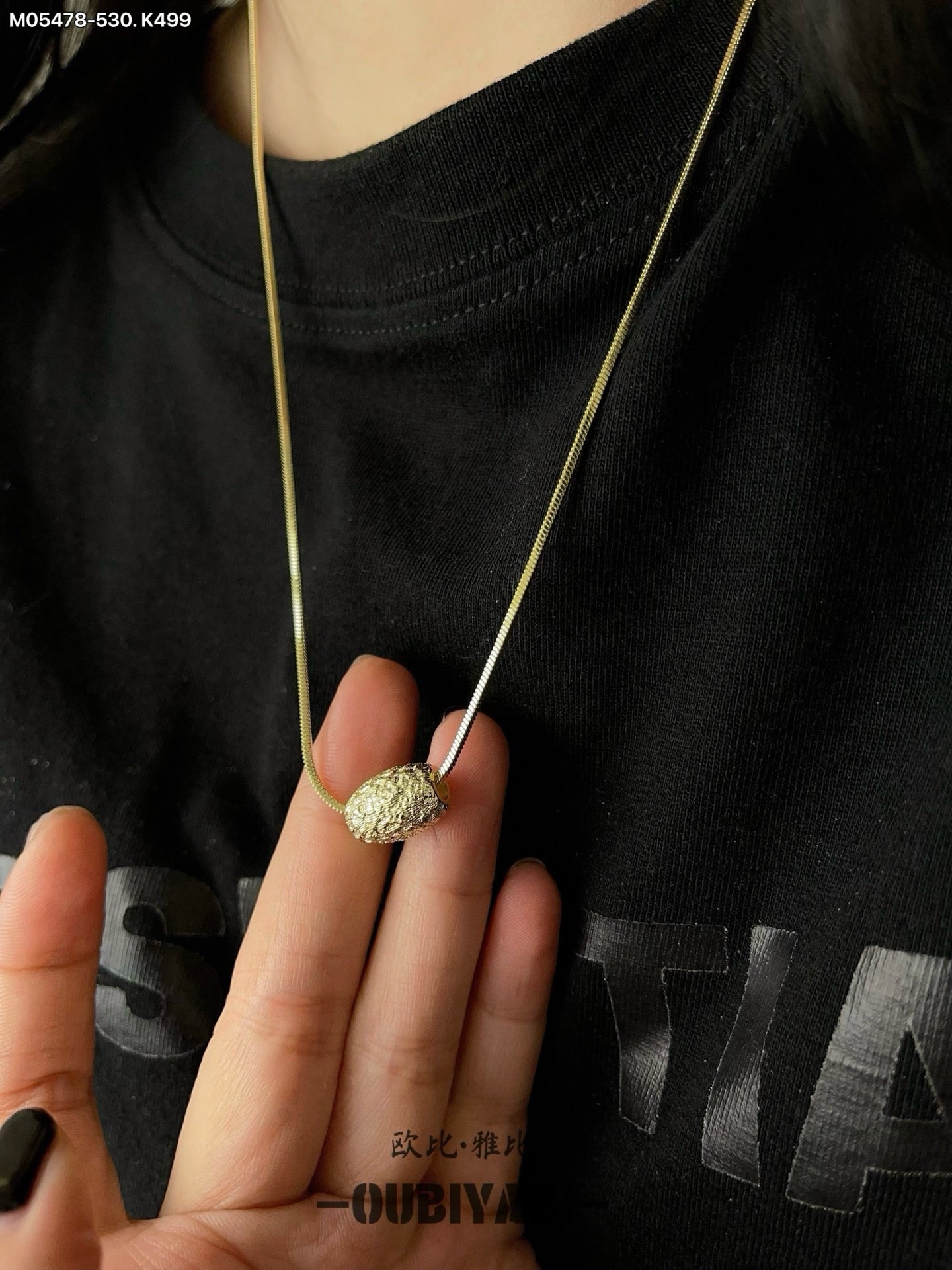 Two-tone metal necklace with silver and gold chains and a carved pendant.