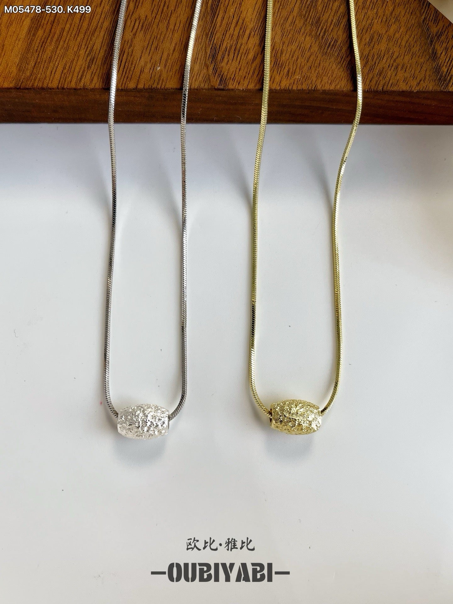 Two-tone metal necklace with silver and gold chains and a carved pendant.