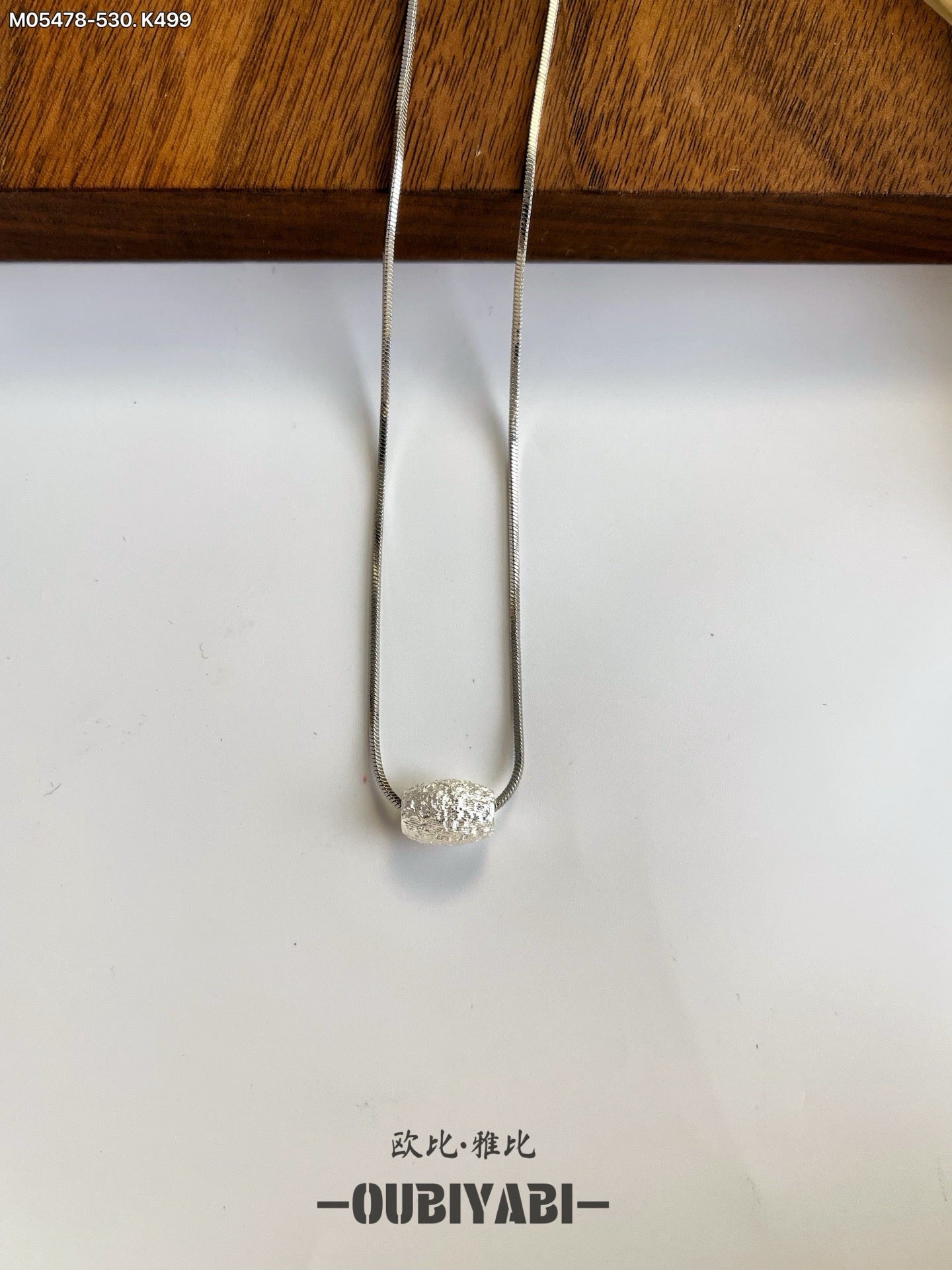 Two-tone metal necklace with silver and gold chains and a carved pendant.